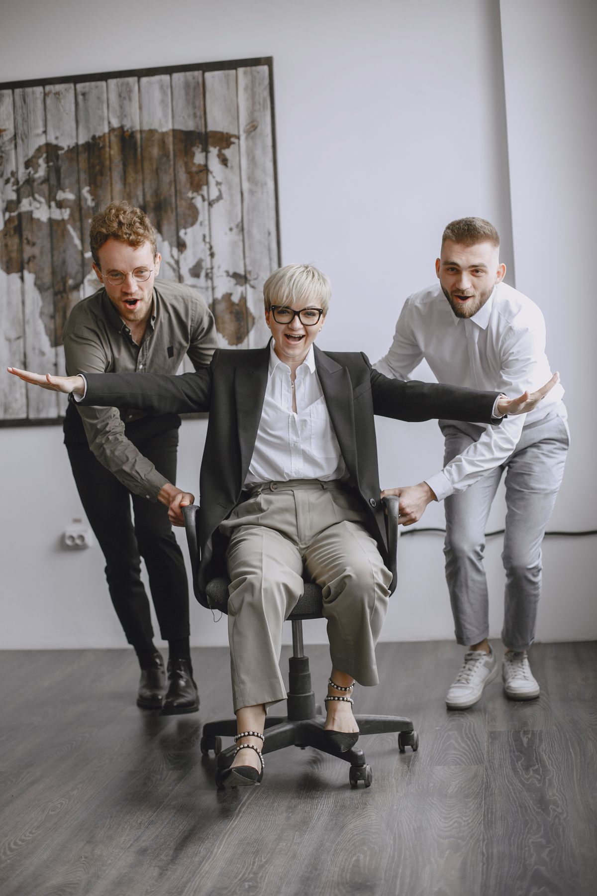 Colleagues playfully racing on office chairs
