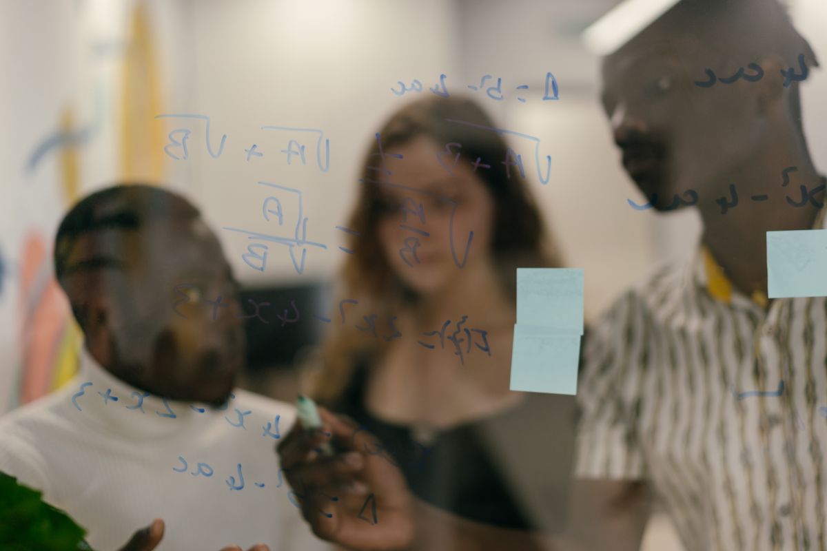 Team solving equations together on a glass board